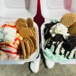 Two styrofoam containers of ice cream with waffle cones