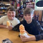 Two boys holding ice cream cones at a restaurant table