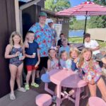 Group of children and adults enjoying ice cream on a lakeside deck