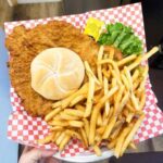 Breaded fried chicken sandwich with fries on checkered paper