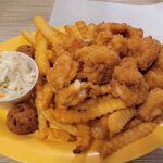 Plate of fried chicken tenders with crinkle-cut fries and coleslaw