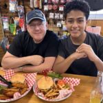 Two people sitting at a table with baskets of fried food