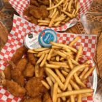 Two baskets of fried chicken tenders and French fries