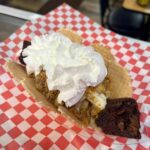 Dessert taco topped with whipped cream on checkered paper