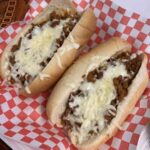 Two loaded chili cheese hot dogs on red checkered paper