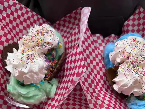 Two colorful ice cream sundaes with whipped cream and sprinkles