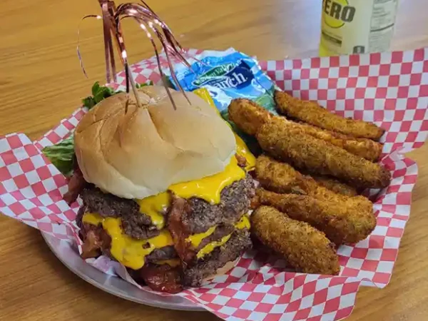 Bacon cheeseburger with fried sides on a checkered tray
