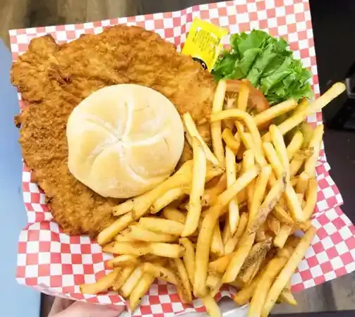 Fried tenderloin sandwich with fries and lettuce on a checkered tray